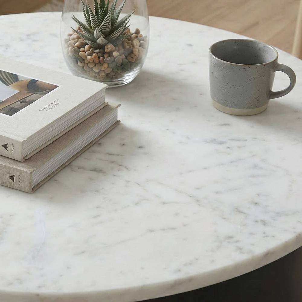 Weiß-graue Marmor-Tischplatte eines Design-Sofatisches mit dekorativen Büchern und Tasse – Lameiro