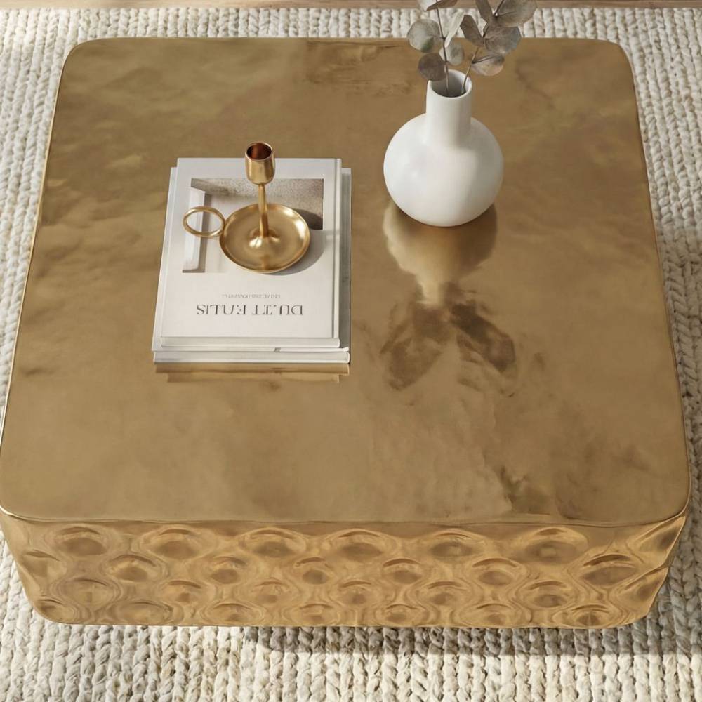 Goldfarbener quadratischer Couchtisch mit gehämmertem Design auf einem hellen Teppich – Zalio