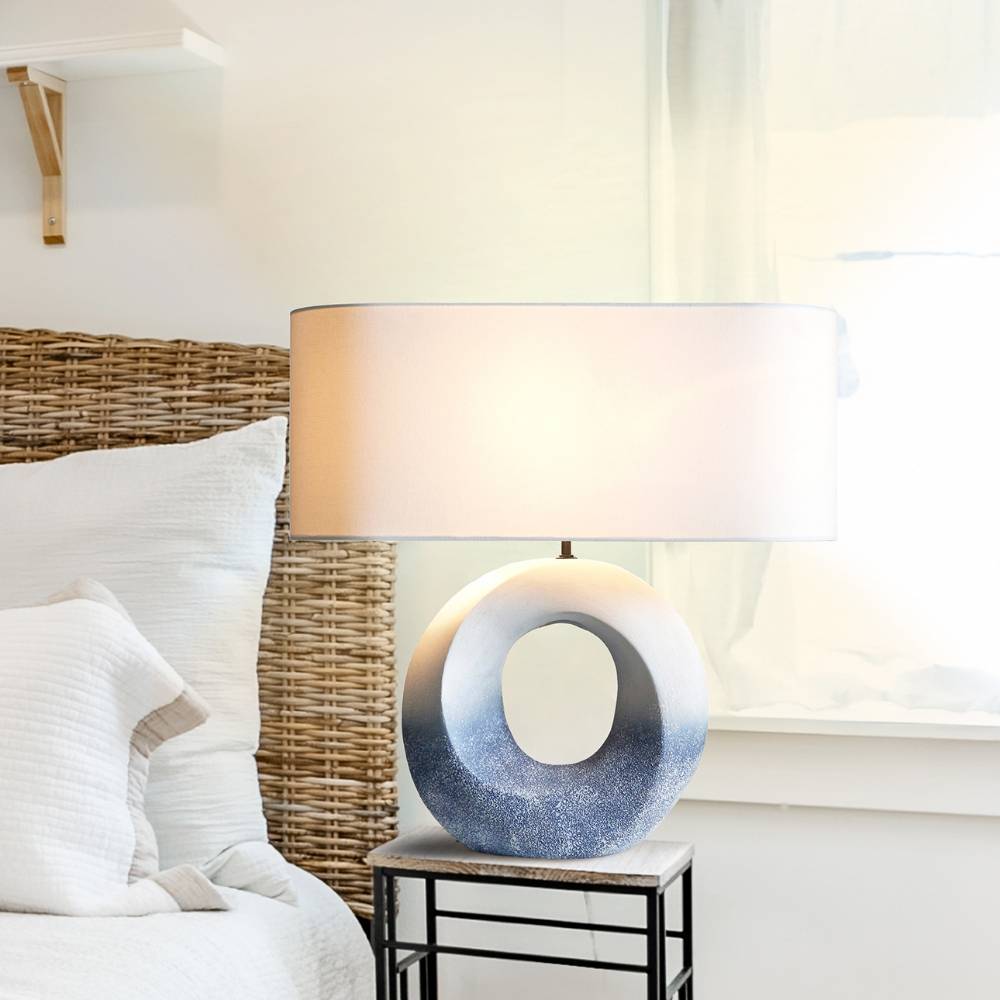 Leuchtende Tischlampe mit hellem Textilschirm und modernem blau-weißem Keramikfuß – Lidello