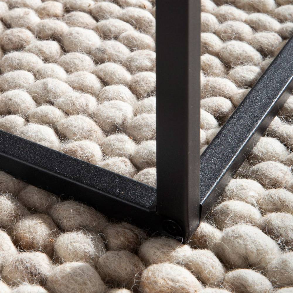 Stabiles schwarzes Metallgestell des Couchtisches auf einem beigefarbenen Teppich – Novo