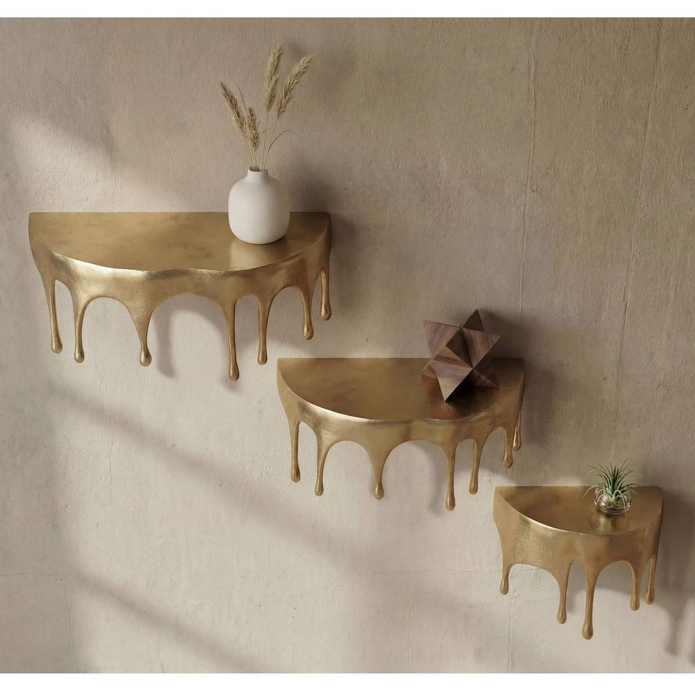 Dreiteiliges goldenes Alu Wandboard Trio an beiger Wand mit geschwungener, tropfenähnlicher Form – Maraga